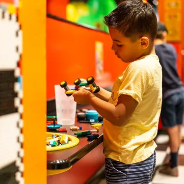 Little boy building a car with lego