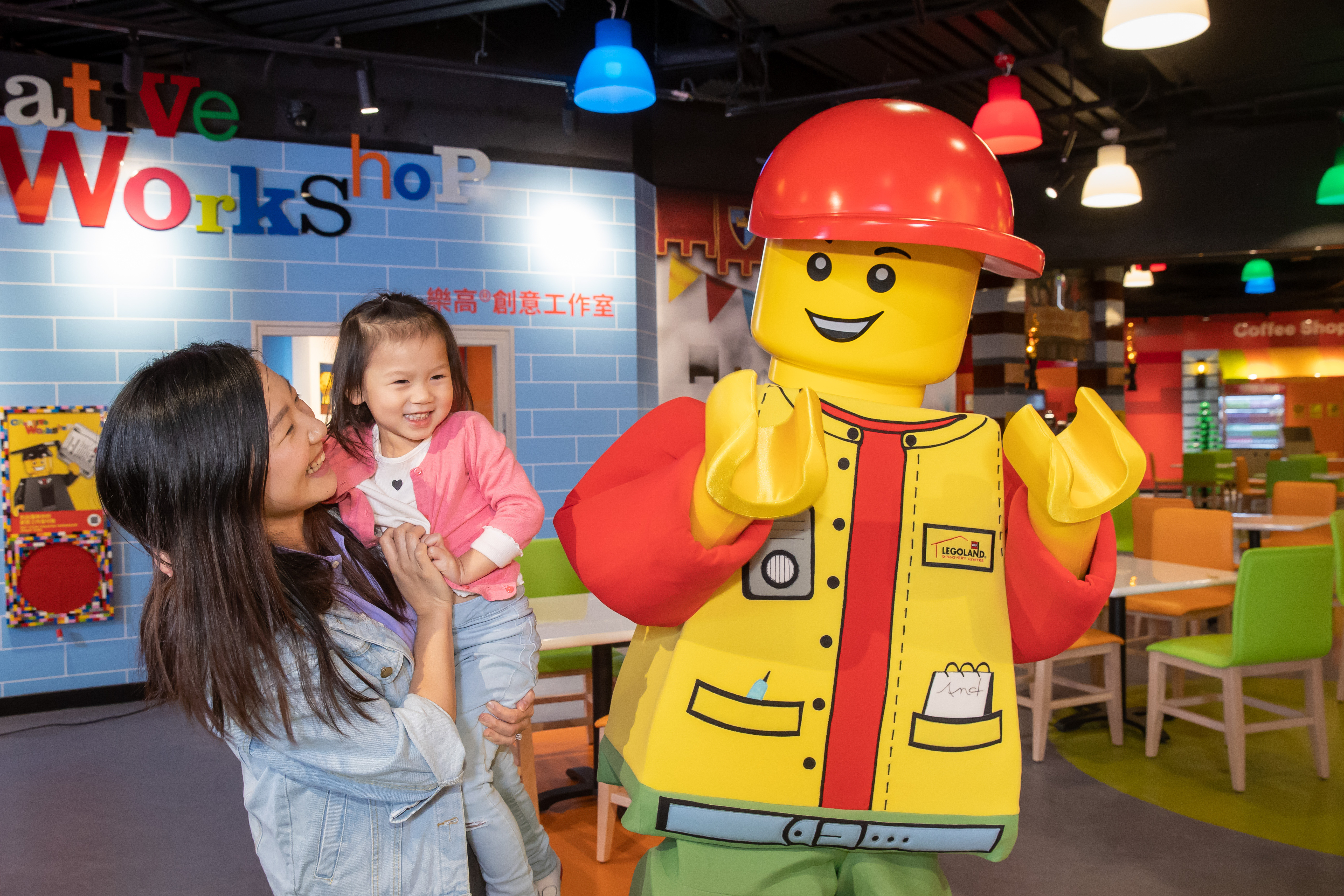 A mother carrying her child as they interact with life-sized LEGO character at LEGOLAND Discovery Centre Hong Kong. 
