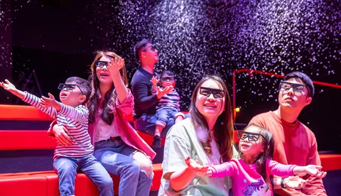 家長和小朋友在室內樂高®4D動感體驗主題展區觀看3D影片